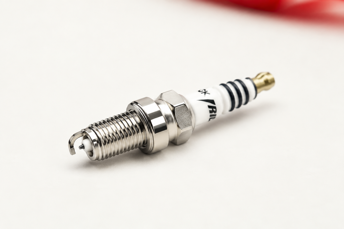 NGK iridium spark plug for a motorcycle on a bone white studio background