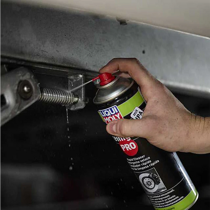 Hand using a can of LIQUI MOLY spray on a car part.
