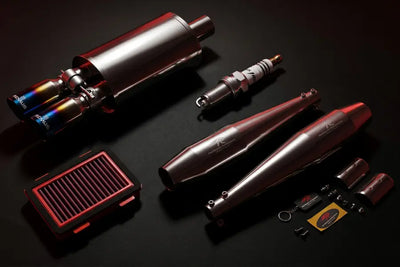Collection of performance automotive parts including exhaust pipes and filters on a dark background