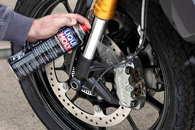 Liqui Moly Motorbike Chain and Brake Cleaner being sprayed onto a motorcycle brake disc