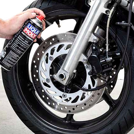 Liqui Moly Motorbike Chain and Brake Cleaner being sprayed onto a front wheel and brake disc