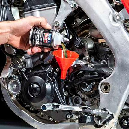 Liqui Moly Motorbike Engine Flush Shooter being poured into a motorcycle engine through a funnel
