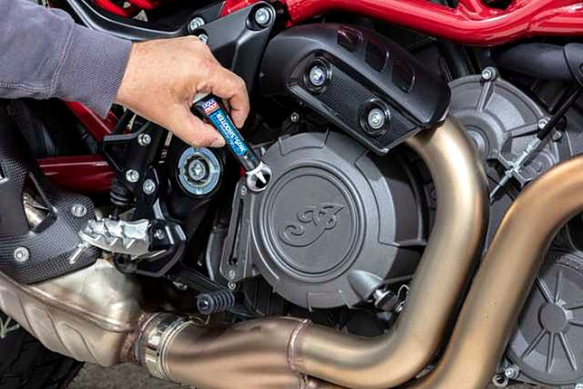 Liqui Moly Motorbike MoS2 Shooter tube being emptied into a motorcycle engine oil filler