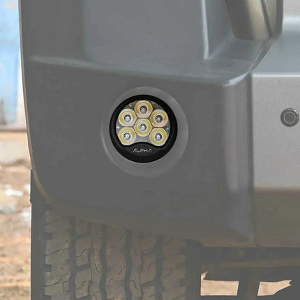 Close-up of off-road bumper with Alpha LED pod light installed, showcasing rugged tire tread.